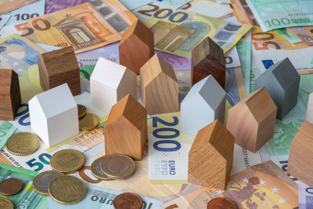 Tiny,Wooden,House,Models,On,Euro,Coins,And,Banknotes.,Concept