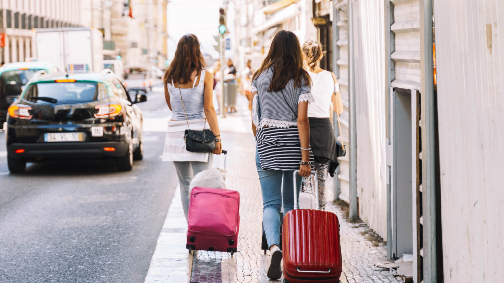 Girls,With,Backpacks,Walking,With,Colorful,Suitcases,To,A,City