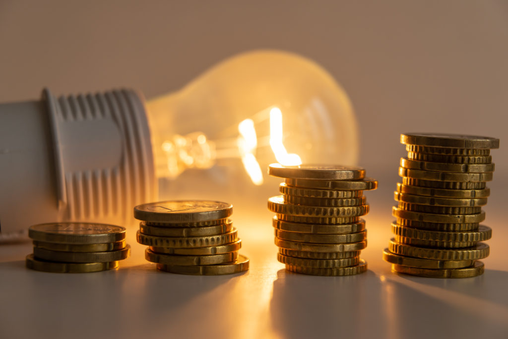 Lit,Light,Bulb,With,Coins,Beside,It.,Increase,In,Energy