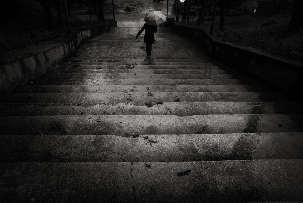 The,Descent/a,Person,Going,Down,The,Stairs,With,An,Umbrella