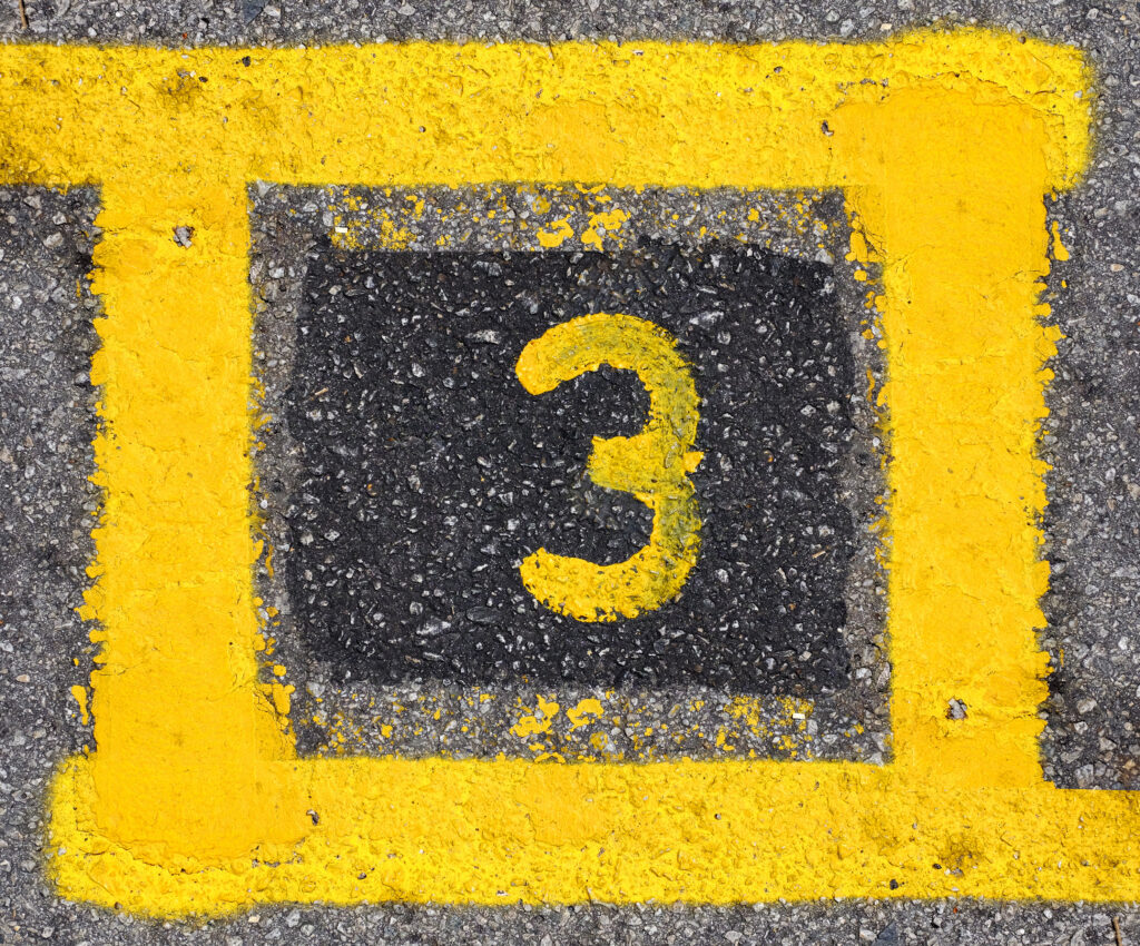 Yellow,Imprint,Of,The,Number,Three,On,A,Tarmac,Road.