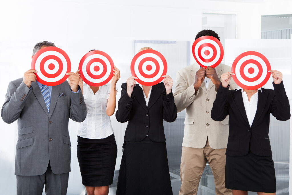 Group,Of,Businesspeople,Holding,Dartboard,In,Front,Of,Face