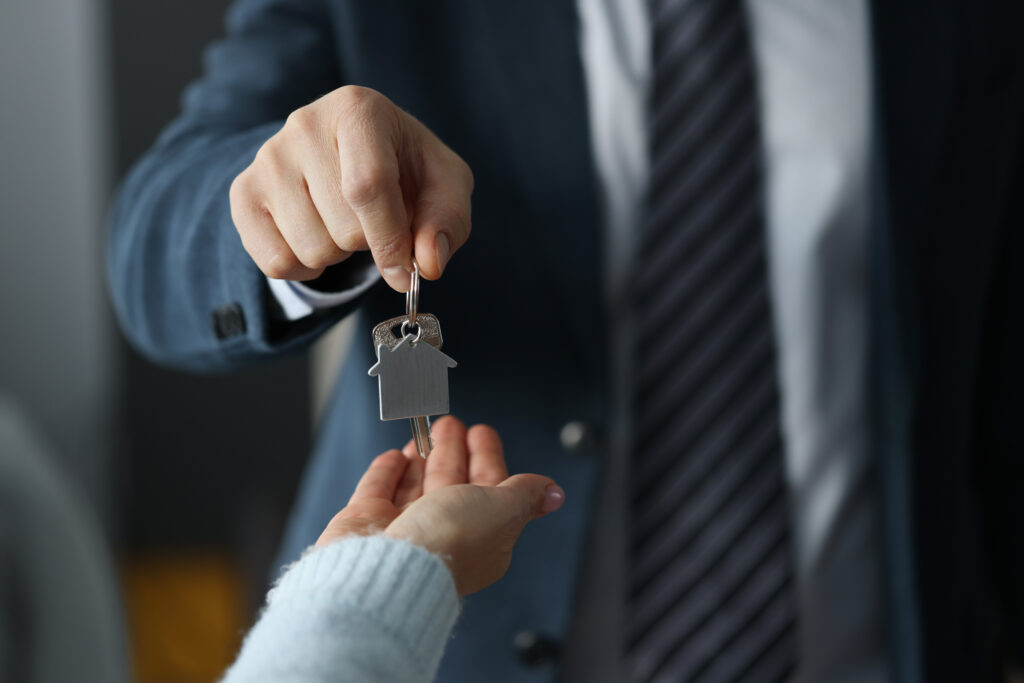 Man,In,Business,Suit,Hands,Overing,House,Keys,To,Woman