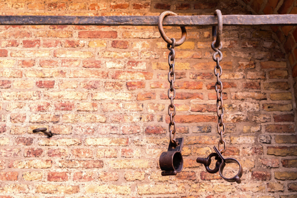 Middle,Aged,Prisoners,Chains,And,Cuffs,Over,A,Brick,Wall
