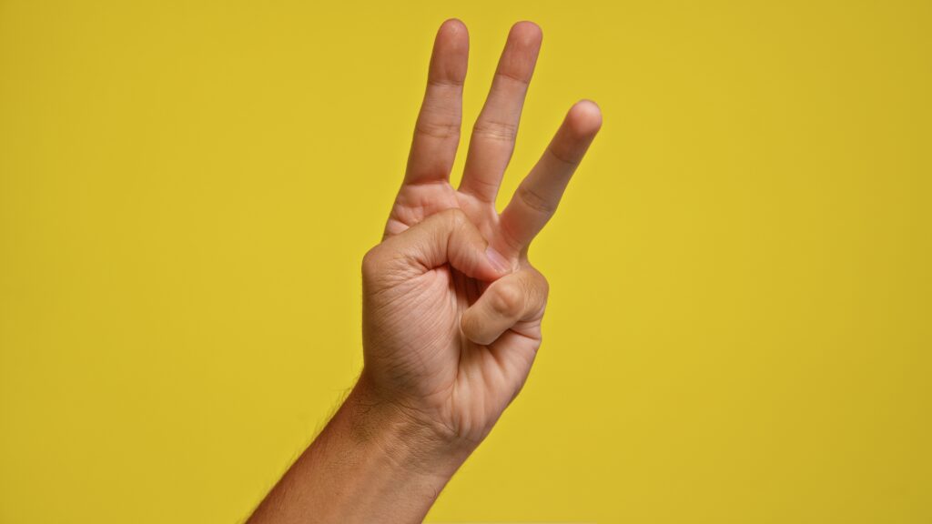 Man,Holding,Up,Three,Fingers,Against,A,Bright,Yellow,Background Shutterstock/Krakenimages.com